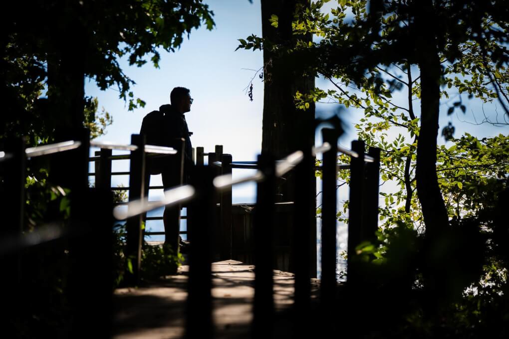 Travis Snyder looks out over Lake Michigan from a platform. Photo is almost a silhouette.